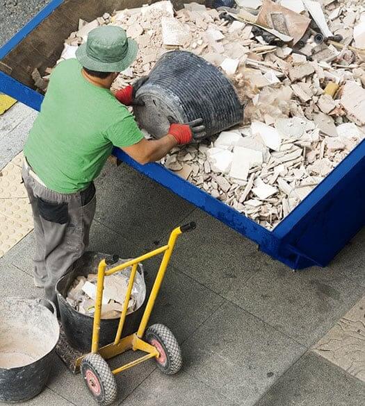 Man Disposing of Construction Debris in dumpster rental