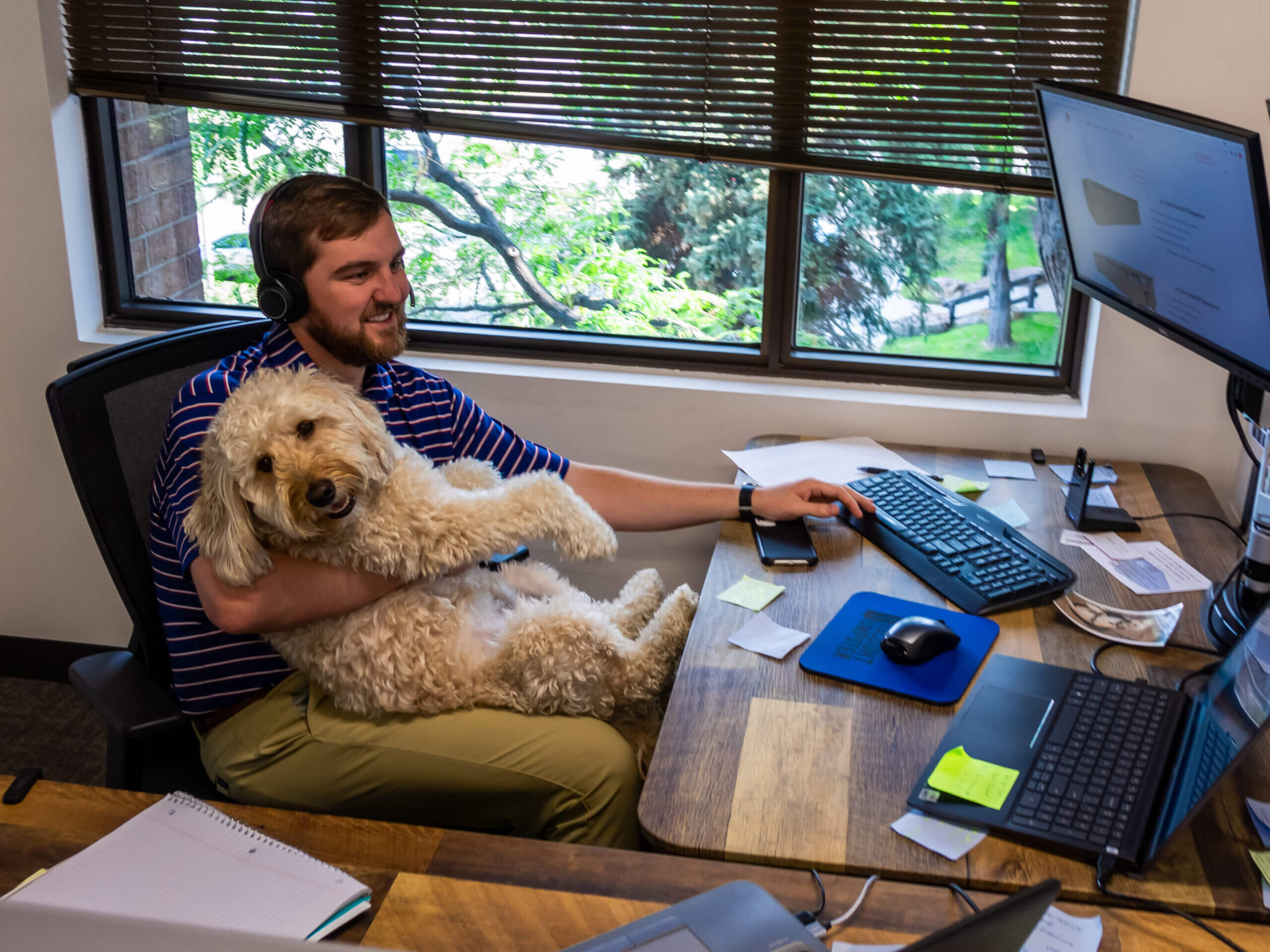 A dumpster rental sales person taking calls with a dog on his lap