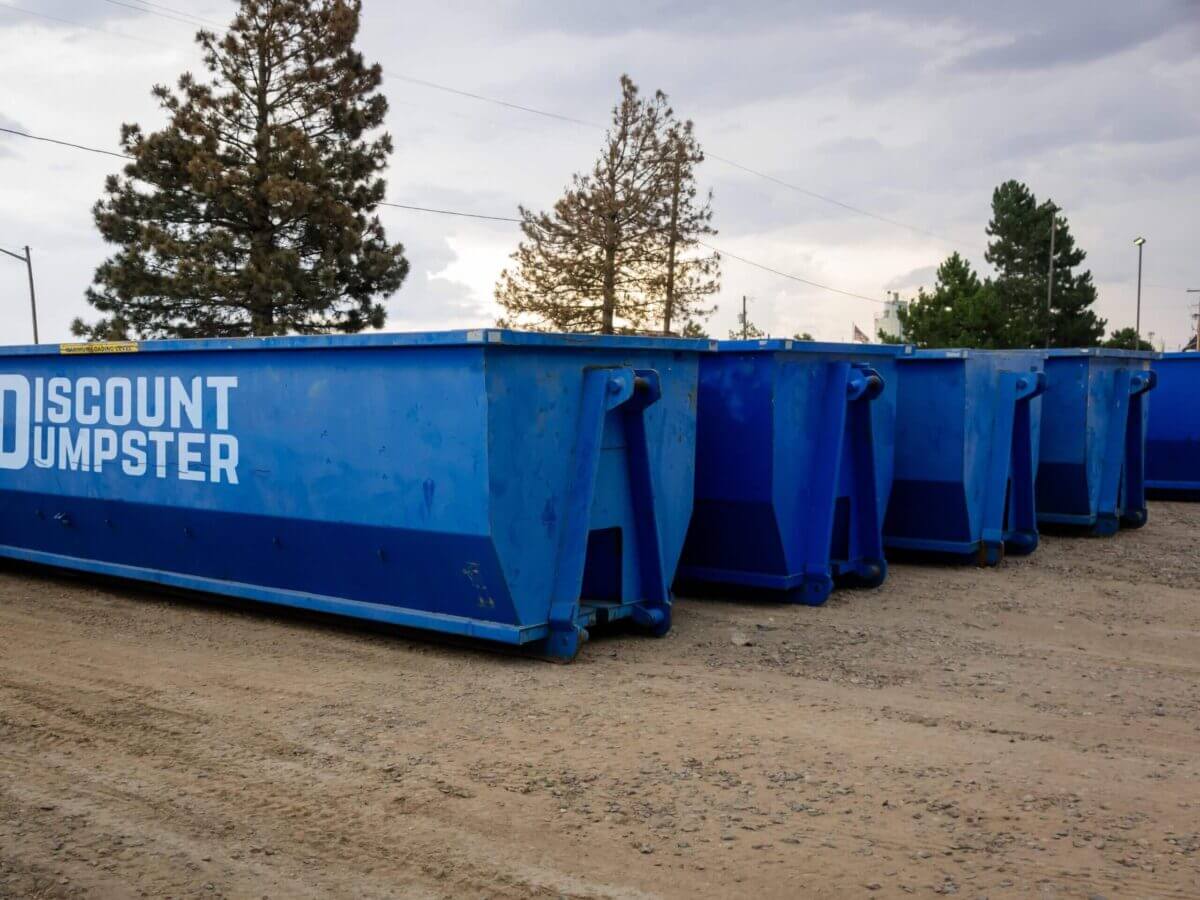 A row of blue 30 yard roll off discount dumpsters