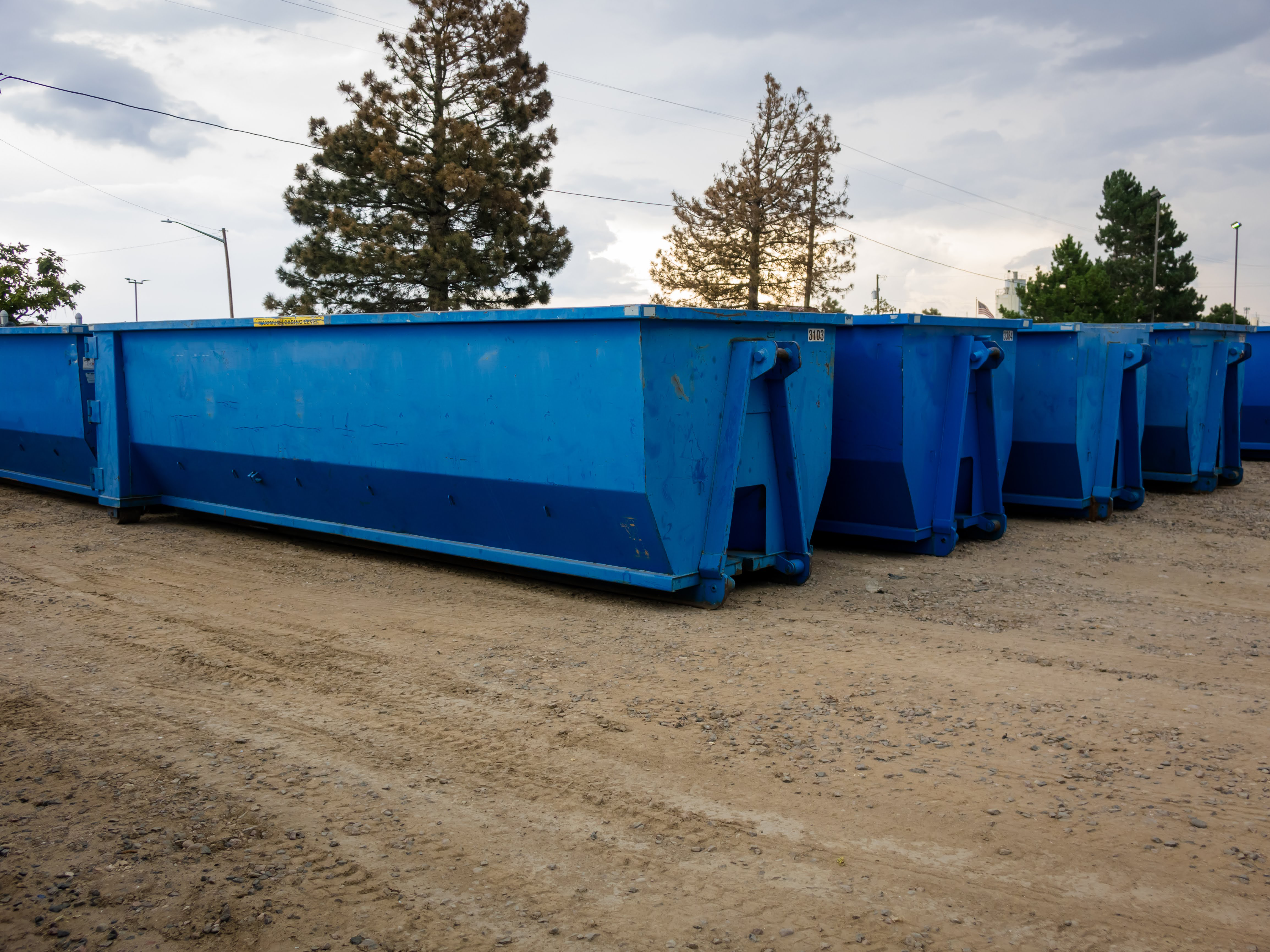 Multiple roll off dumpsters parked in a line