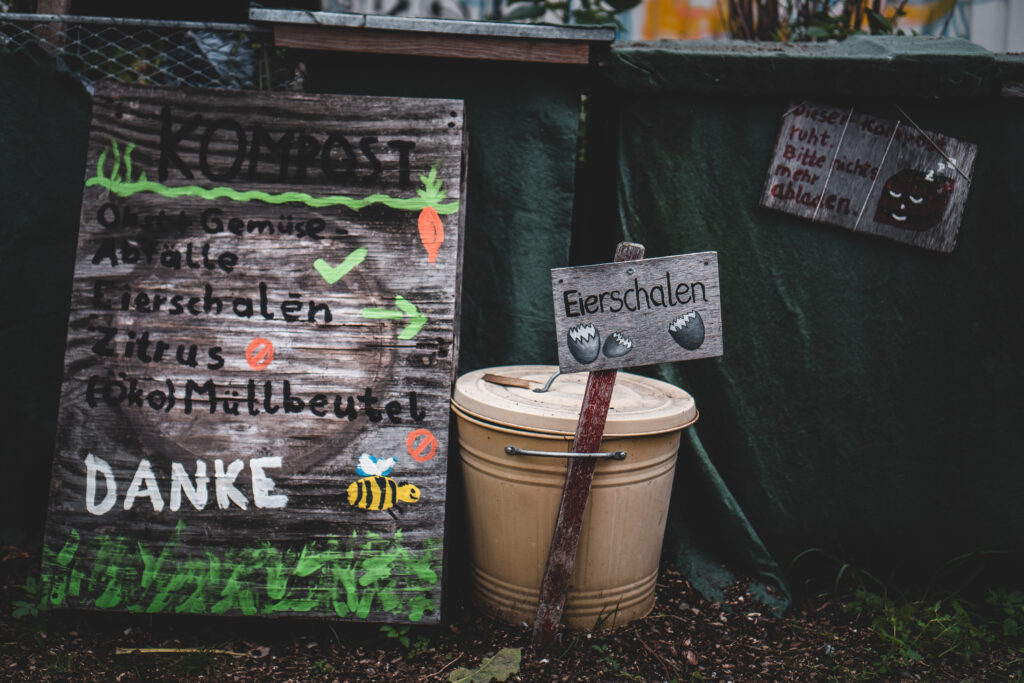 a composting container next to a sign with german words painted on it
